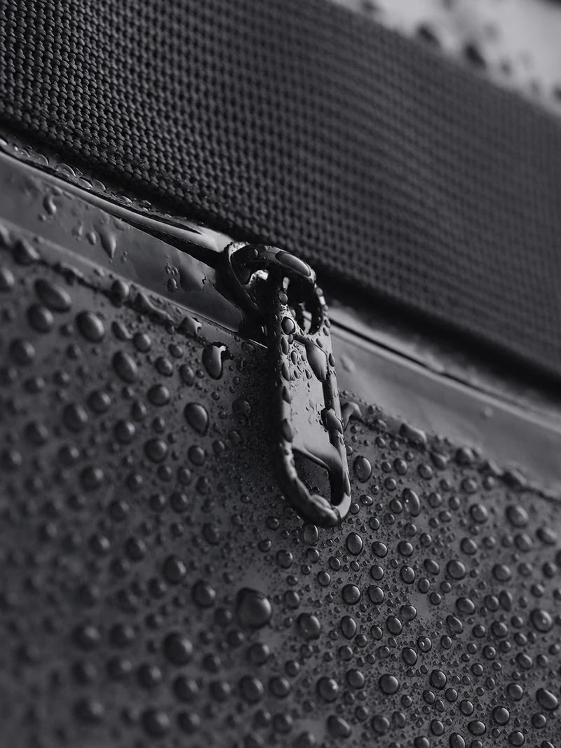 Des gouttes d’eau sur le tissu noir et la fermeture éclair CISTA.